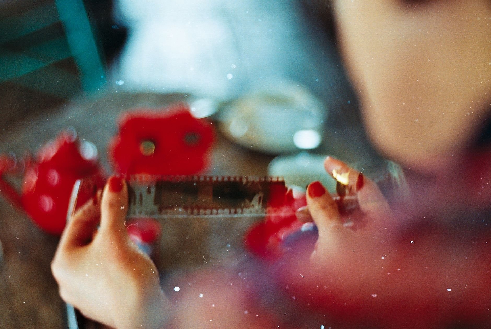 Close-up of hands holding a film strip, vintage aesthetic with red tones.